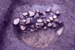 多くの焼けた石が埋められた穴の半分を掘削し、その様子を横から撮影した写真です